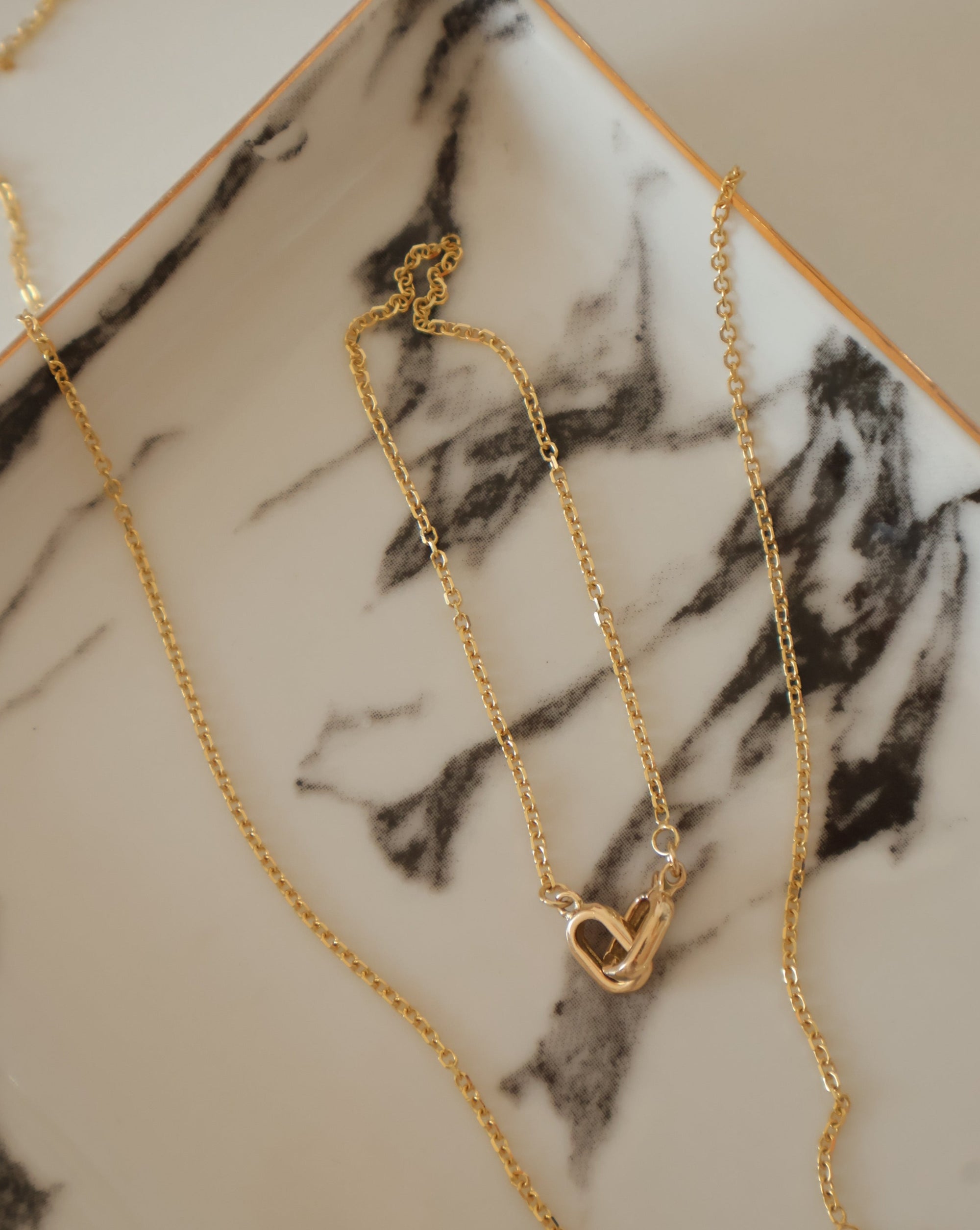 marble dish holding 14k gold bracelet and necklace set