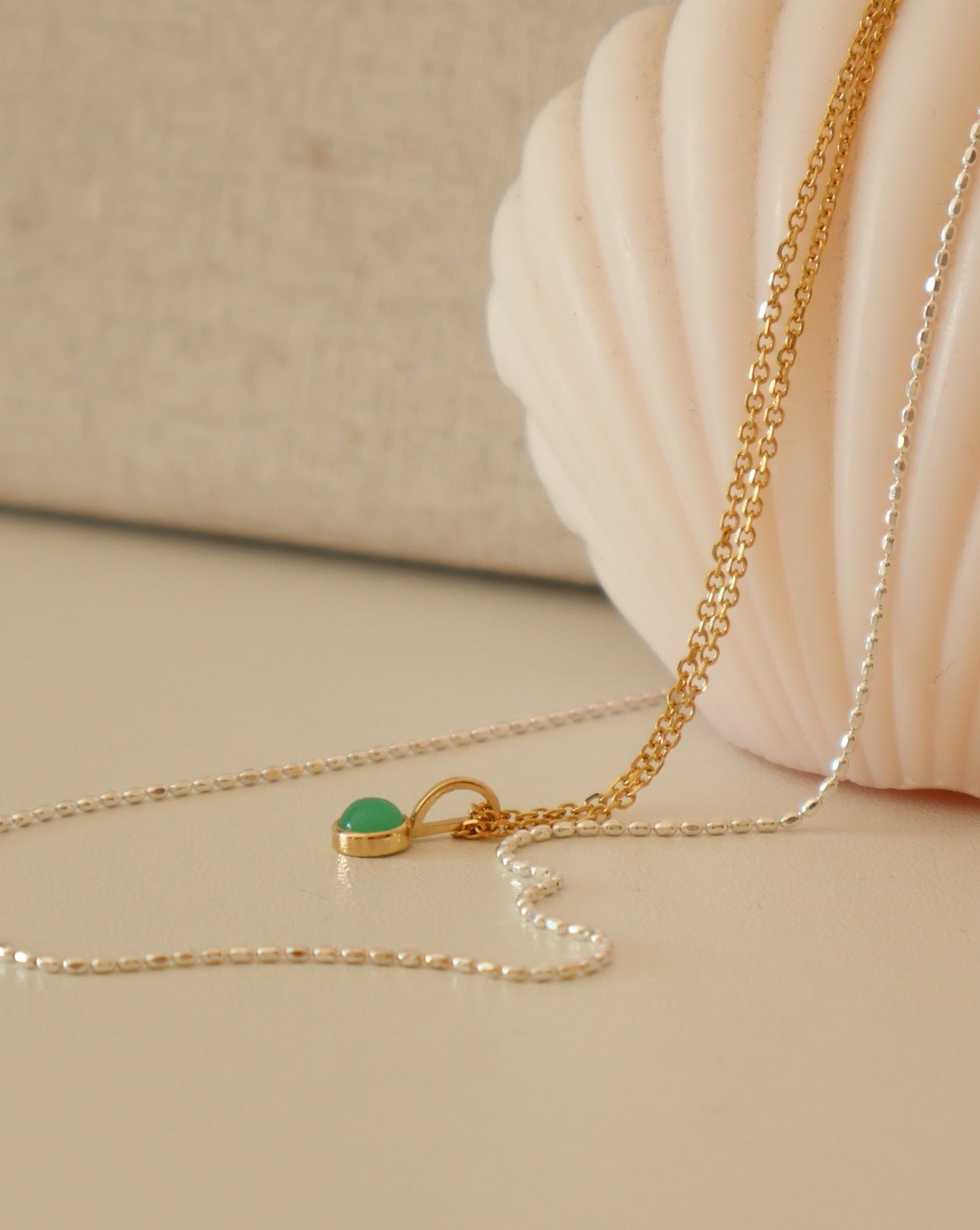 two necklaces draped on a soft peach candle