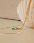 two necklaces draped on a soft peach candle