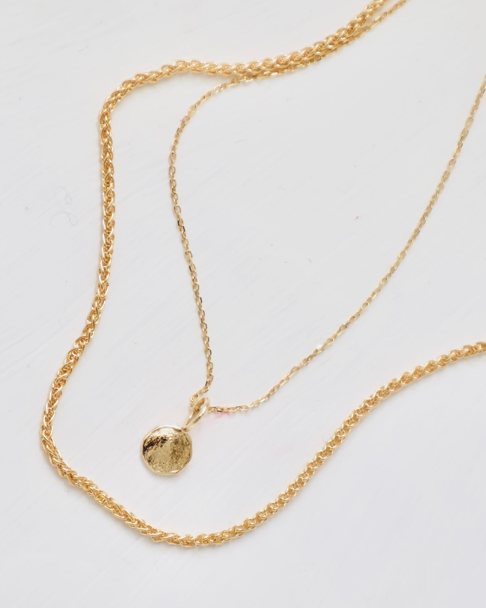 two 14 karat gold necklaces featuring a mini disc pendant with texture. An easy to wear necklace pair for classic style