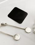 small black anti-tarnish tabs next to silver jewelry on a white dish