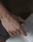 gold and diamond compass charm on a paperclip chain bracelet