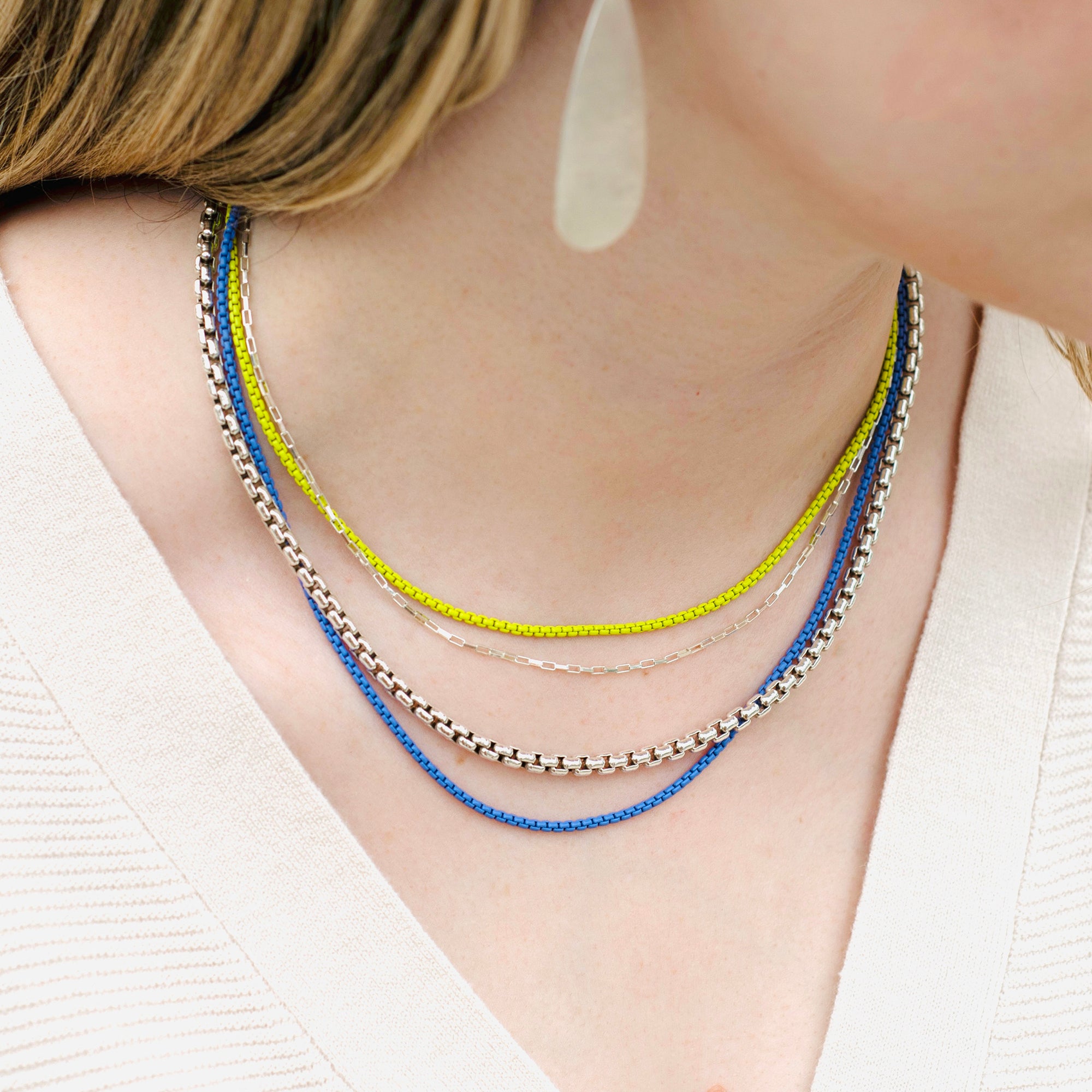 women wearing four sterling silver necklaces with two color coated chains and a heavy box chain