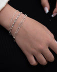 women wearing three sterling silver bracelets with paperclip style links and french manicure