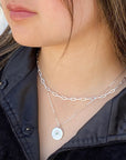 women wearing two silver necklaces with an emerald pendant