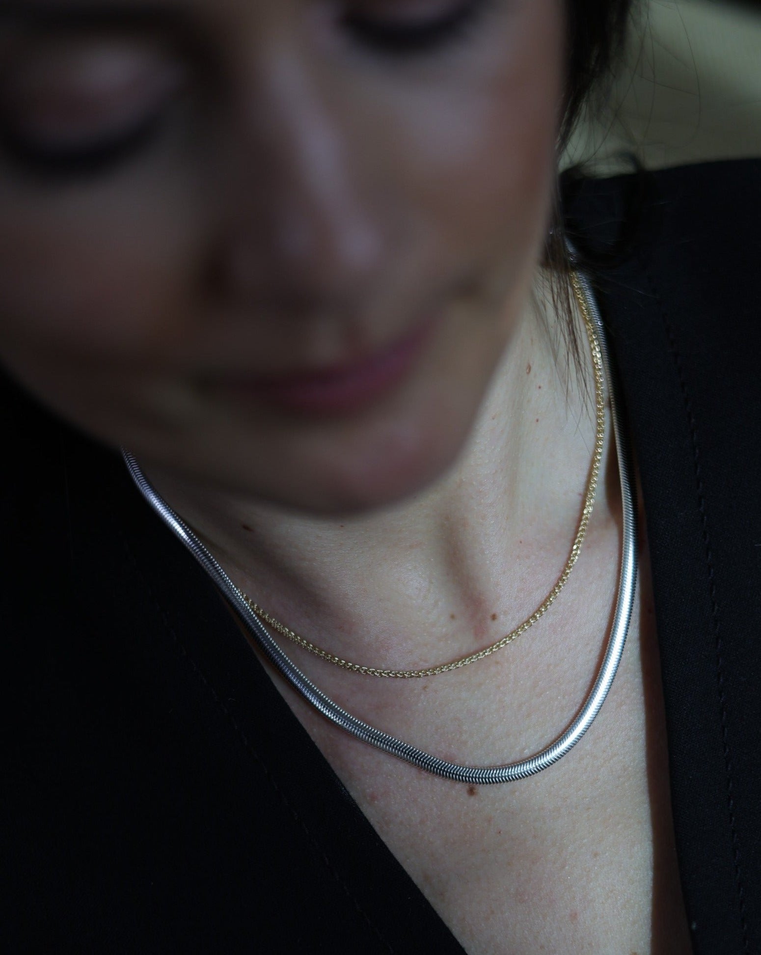 elegant women wearing a sterling silver herringbone snake chain paired with a solid 14 karat gold rope chain