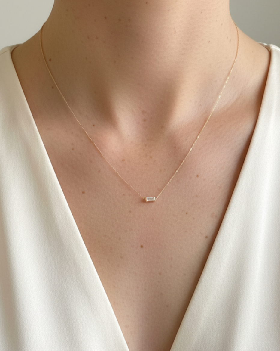 Women wearing a dainty gold necklace featuring a baguette style diamond pendant by Sincerely Chain Co.