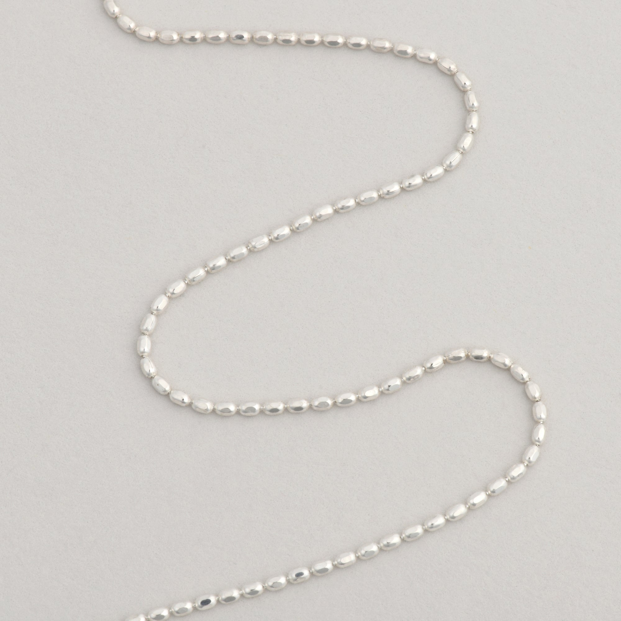 aesthetic silver beaded necklace on grey background