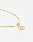 solid gold mini disc pendant with subtle texture on a delicate 14k gold chain