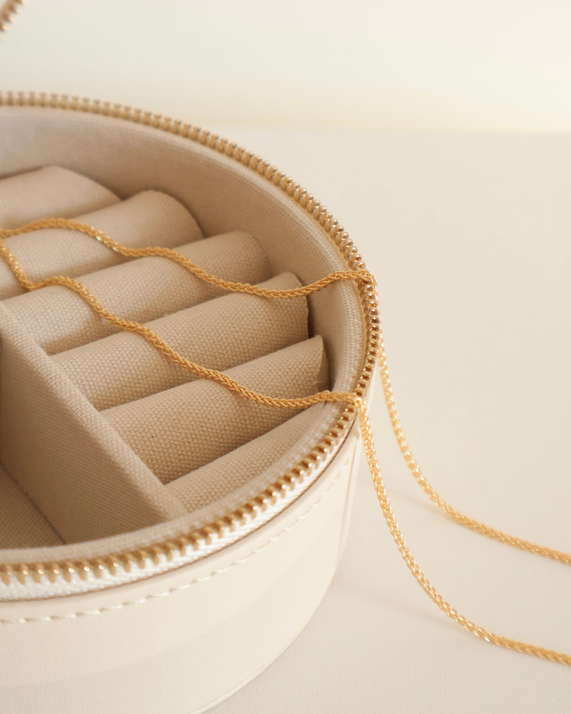 aesthetic round jewelry box with a 14 karat gold necklace made from wheat chain