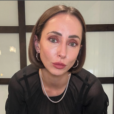 Woman in a black outfit wearing sterling silver necklace by Sincerely Chain Co. holding a handbag indoors.