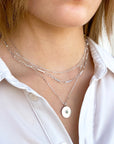 Women wearing three sterling silver necklaces featuring paperclip chains, a simple round pendant by Sincerely Chain Co.