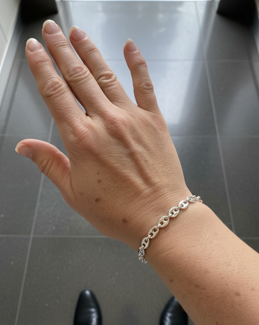 Elegant hand model with bright silver anchor chain bracelet in elevator setting.