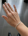Elegant hand model with bright silver anchor chain bracelet in elevator setting.