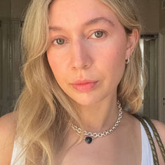 Woman with blonde hair and a white top, wearing a chunky sterling silver necklace by Sincerely Chain Co.