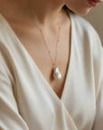 Baroque Pearl on a 14k gold chain necklace on a women in a silk blouse.