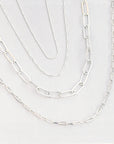 four silver necklaces layered to make a premade necklace stack