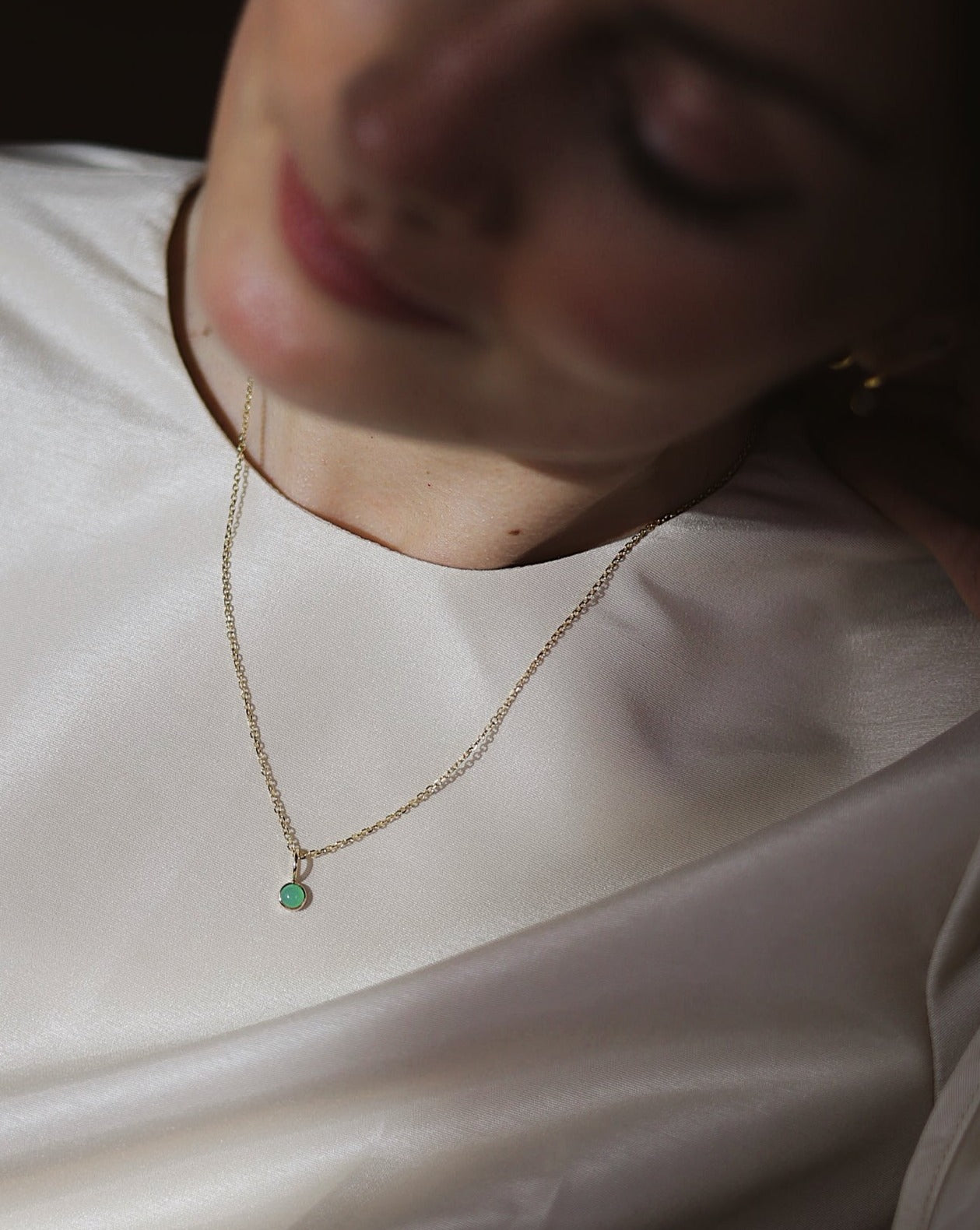 A women wearing a dainty 14K gold chain with a chrysoprase charm pendant, elegant jewelry by Sincerely Chain Co.