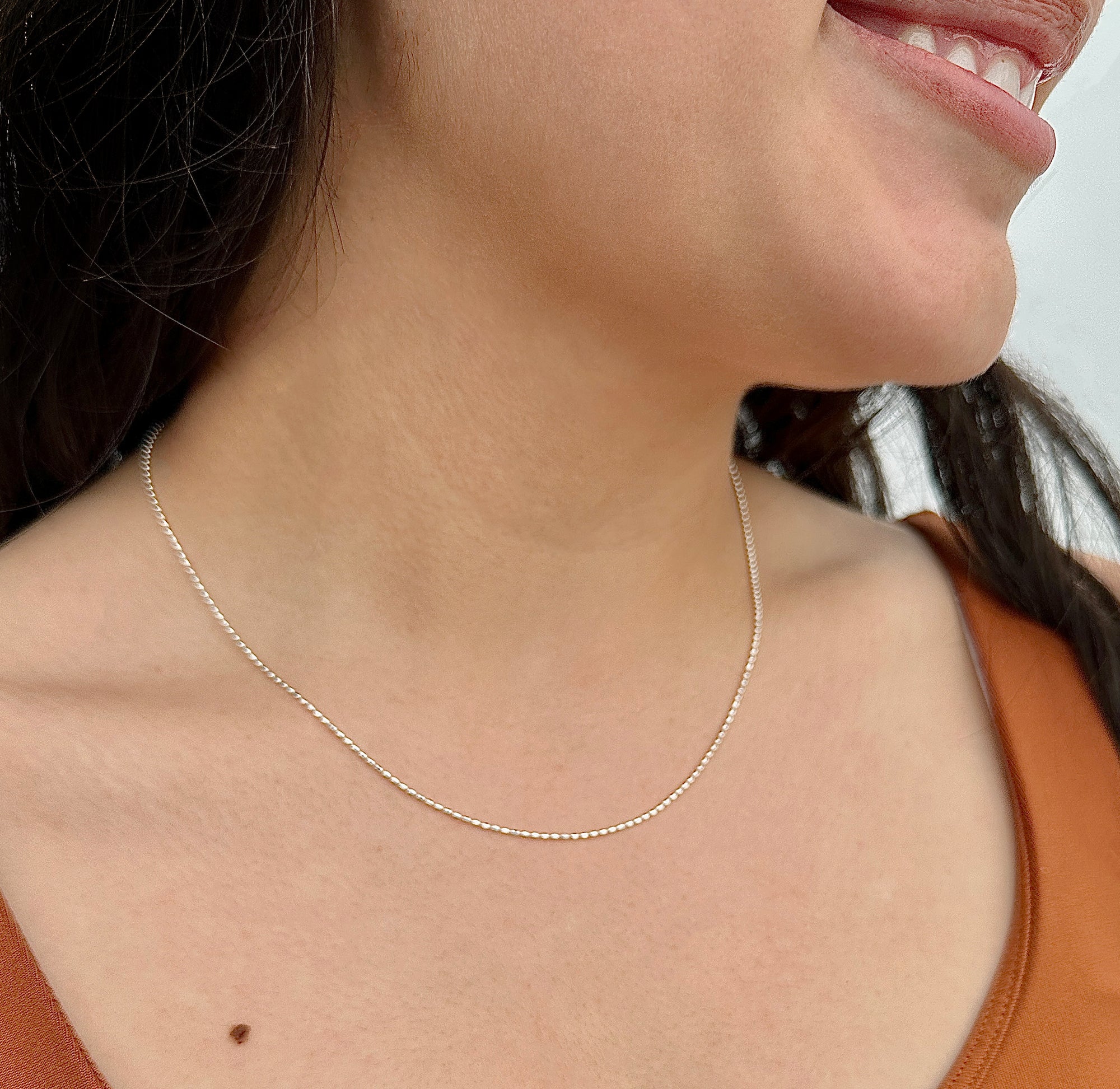 women wearing a dainty silver chain necklace with oval silver beads