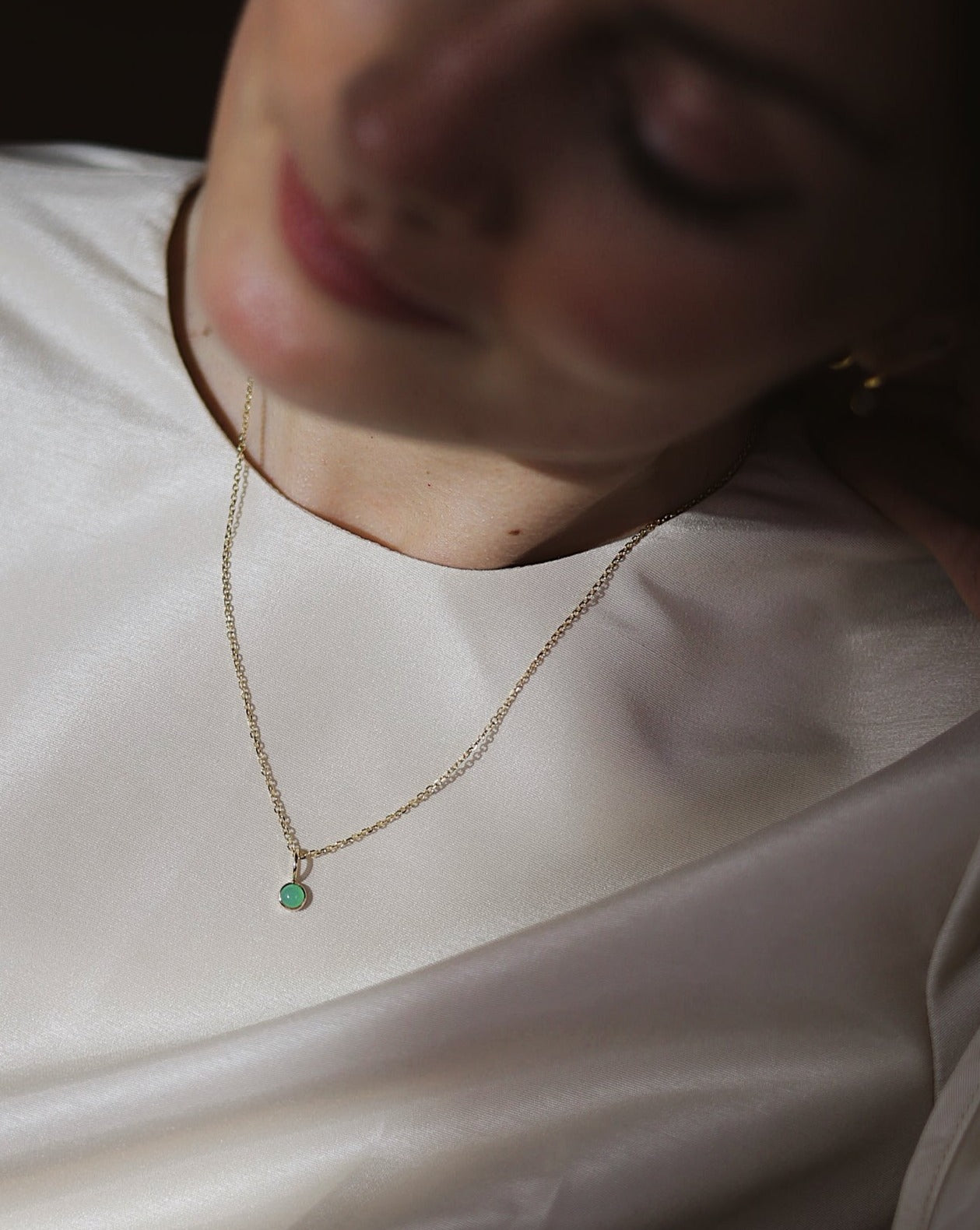 women wearing a dainty gold chain with a chrysoprase charm pendant 