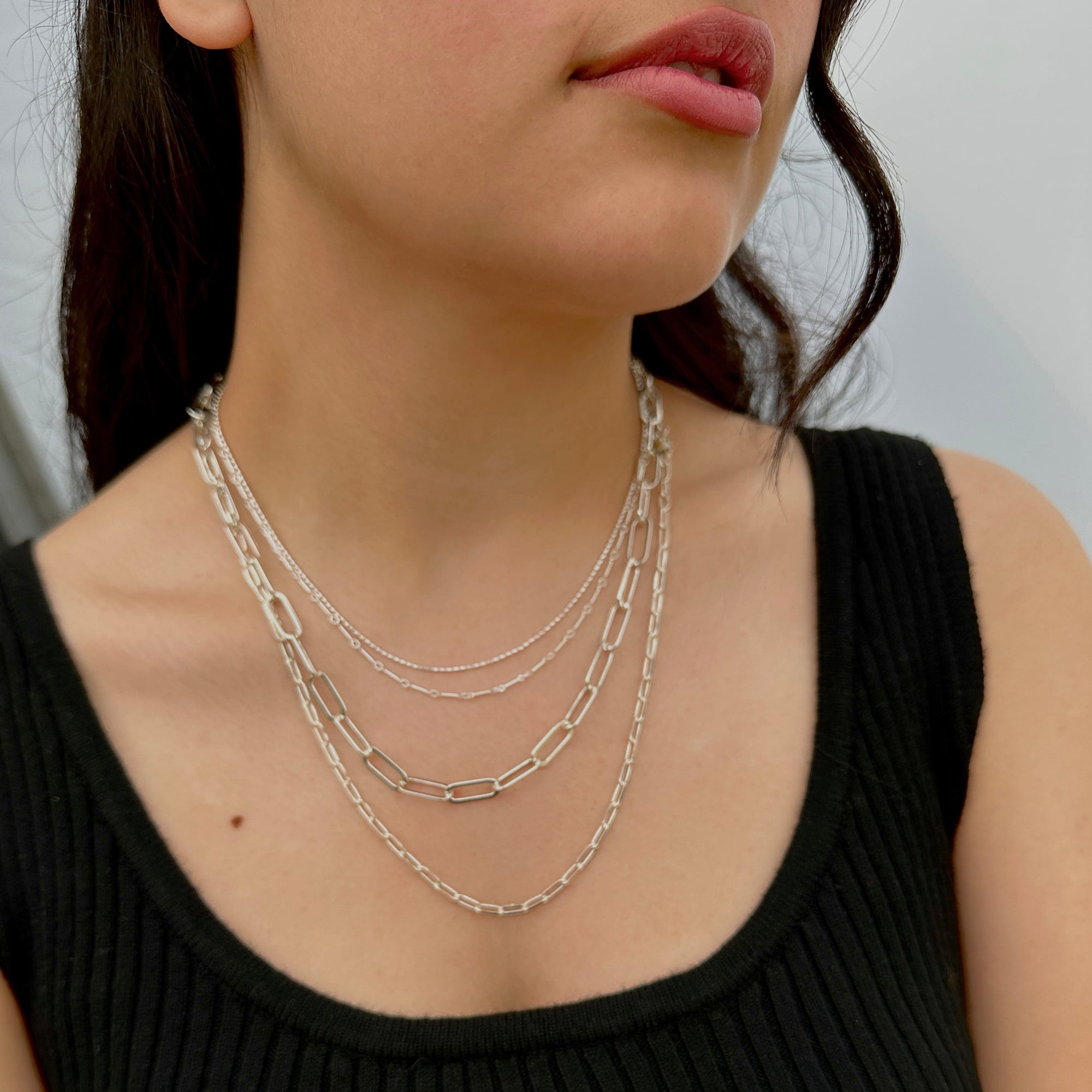 elegant women wearing a silver necklace stack with various chain styles 