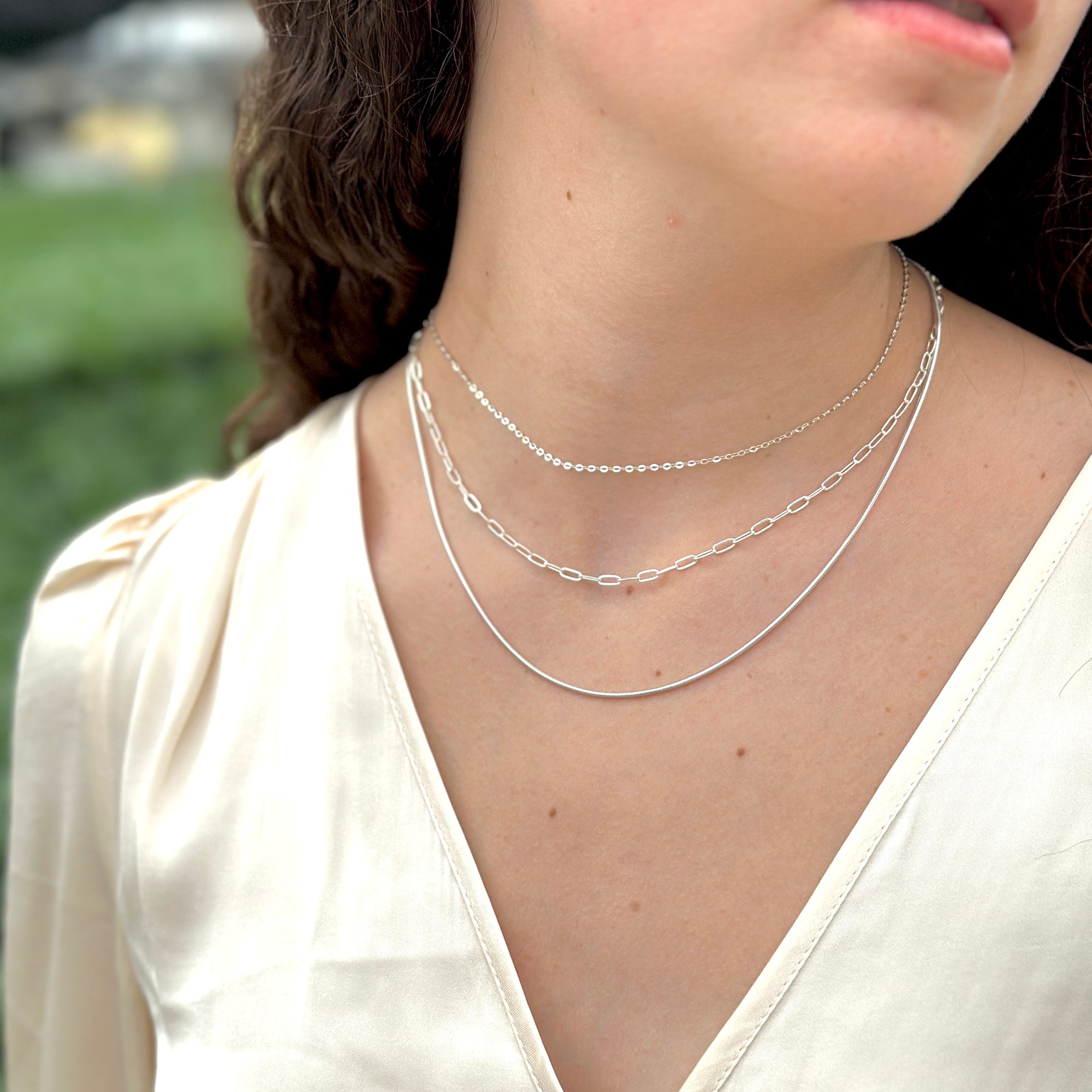 women wearing an elegant three necklace stack in sterling silver chains